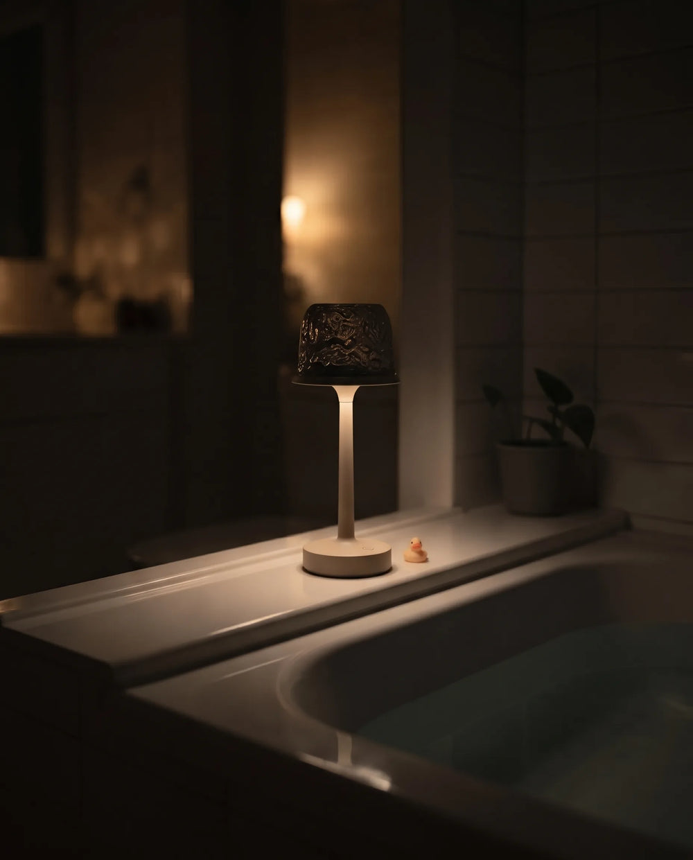 Hush Glow® lamp resting on a bathtub ledge in a dark bathroom
